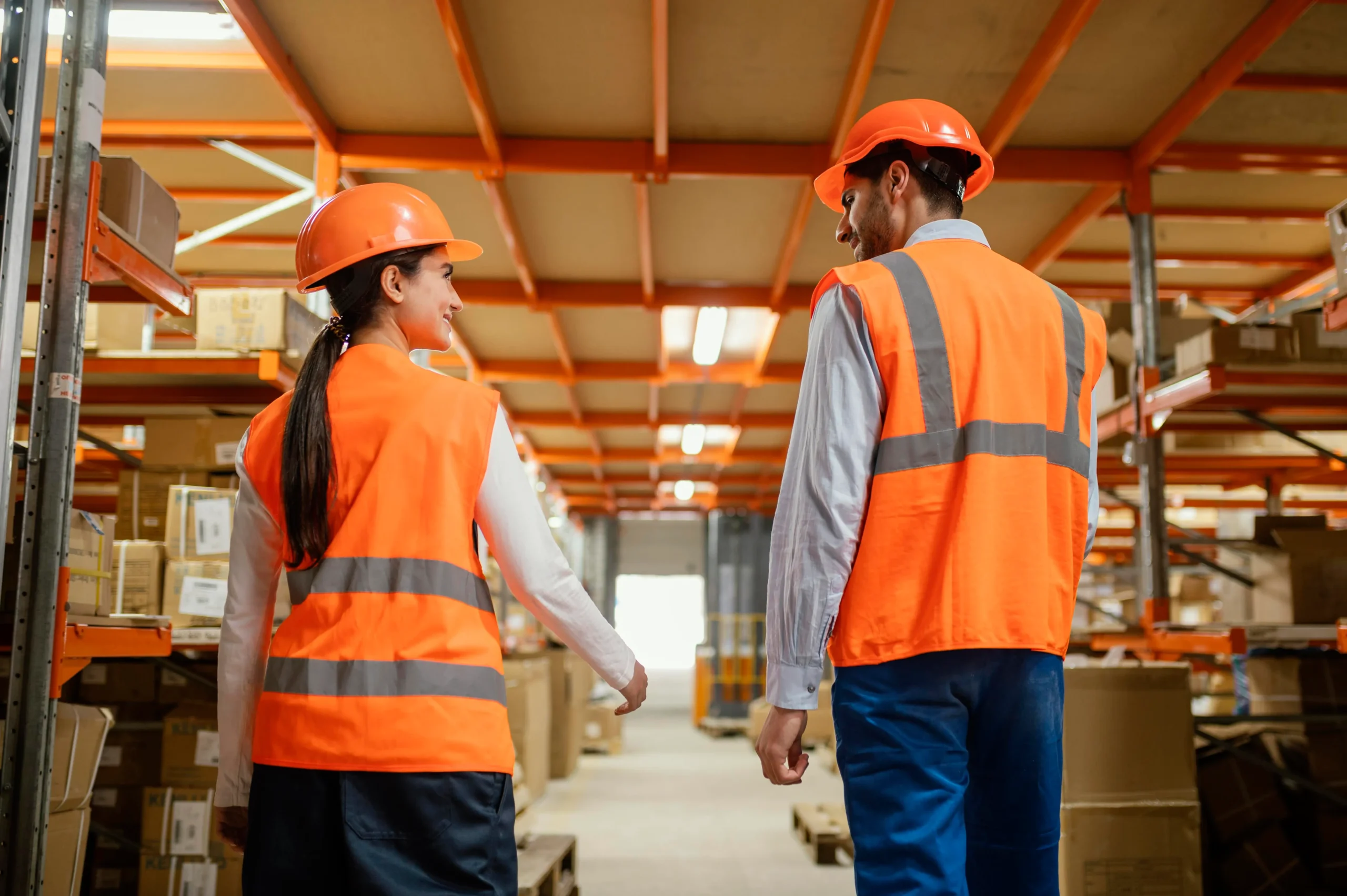 Warehouse workers standing together in a spacious warehouse, surrounded by shelves and equipment.