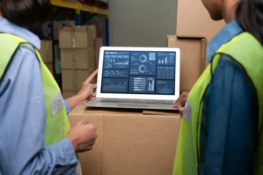 Two warehouse operators analyzing data using a WMS.